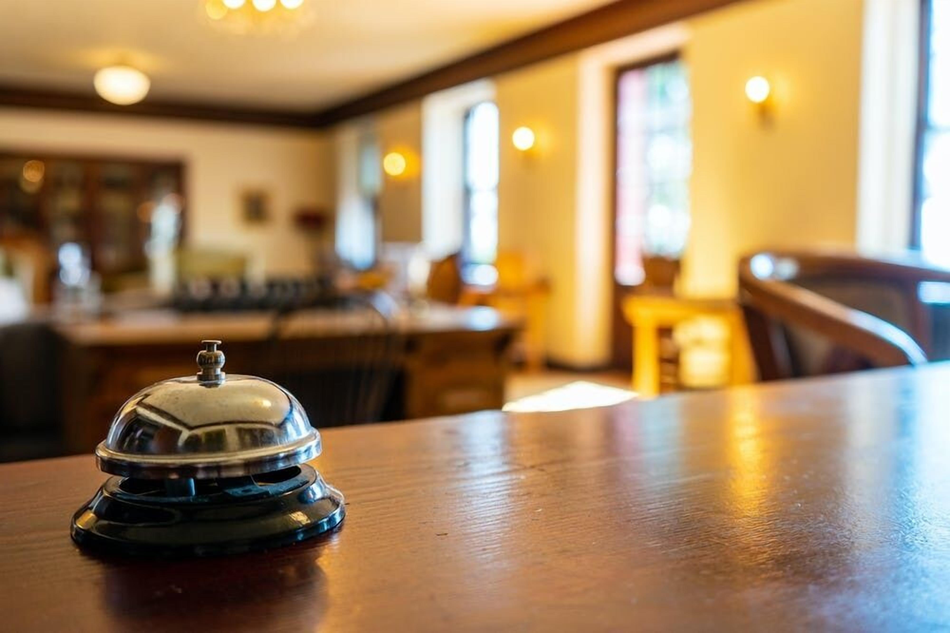 A wooden table with a silver service bell in the foreground.