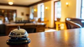 A wooden table with a silver service bell in the foreground.