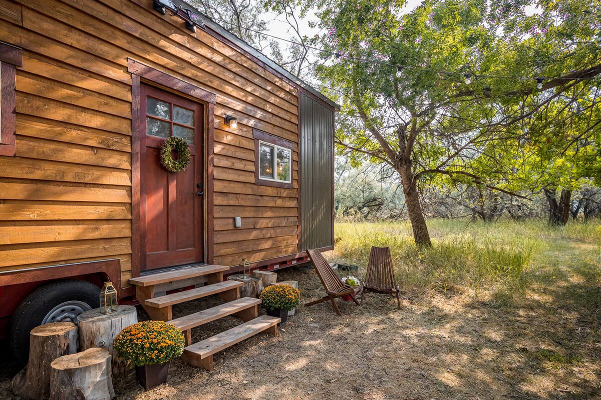 Un rustico chalet con facciata in legno, una porta rossa e un portico con gradini e una panca.