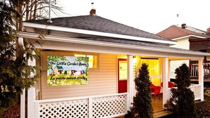 Ein Haus mit Veranda, einem Schild mit der Aufschrift 'The Little Crooked House' und einer roten Tür.