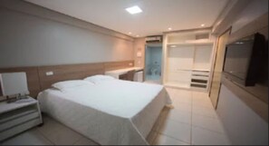 A hotel room with a bed, bedside table, and a TV mounted on the wall.