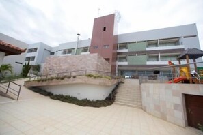A multi-story building with a central courtyard, a staircase leading to the upper levels, and a playground area with slides.