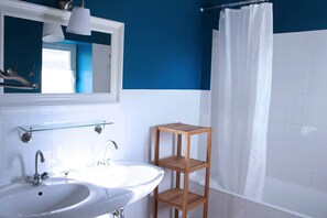 A bathroom with a white sink, a mirror, a wooden shelf, and a white shower curtain. - Le Mauzac, comfort in the heart of nature (CONDOM)