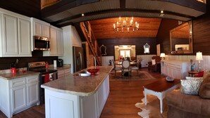 A spacious kitchen with white cabinets, a central island, and a chandelier. - The Bridge House located in an Beautiful RV Resort near Lake Conroe.  (Montgomery)