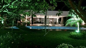 A nighttime view of a modern house with a swimming pool, surrounded by lush greenery and a hammock. - Large 6 rooms Luxury Home with Pool and Hot tub (Aflitos)