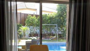 En matplats med ett bord och stolar, utsikt över en swimmingpool och en balkong med gardiner.
