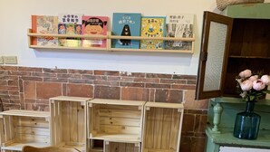 A wooden table with chairs, a coffee pot, and a tissue box. There are books on a shelf above. - Yamaharuka B&B (Jinhu)