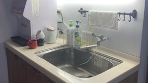A kitchen with a sink, a kettle, a coffee maker, and a bottle of hand soap. - Yamaharuka B&B (Jinhu)