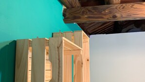 A wooden structure with multiple compartments, possibly a storage unit or furniture, against a teal wall. - Yamaharuka B&B (Jinhu)