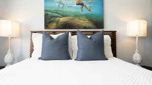 Ein Schlafzimmer mit einem Bett, zwei Kissen, einem Kopfteil und einem Wandbild von Schwimmern.