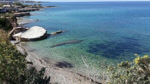 Una zona costiera con acque limpide, rocce e un piccolo molo.
