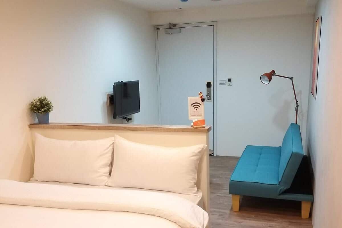 Een slaapkamer met een bed, een bureau, een stoel, een televisie en een lamp.