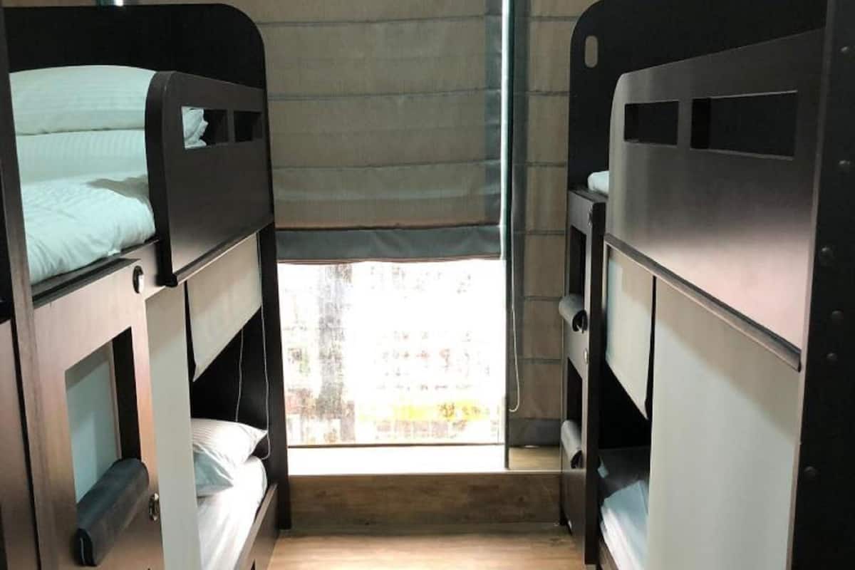 Een kleine kamer met stapelbedden, een raam met uitzicht en een deur.