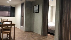Habitació d'hotel amb terra de fusta, un llit, una taula de nit i una finestra.
