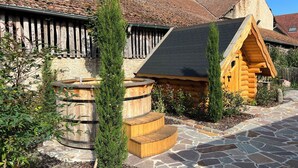 Una cabaña rústica de troncos con un sendero de piedra y escalones de madera que conducen a un barril de madera.