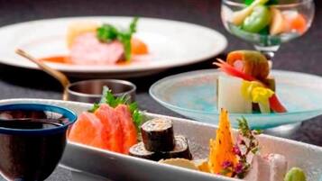 Diversos platos, como sushi y sashimi, servidos en distintos platos y recipientes.