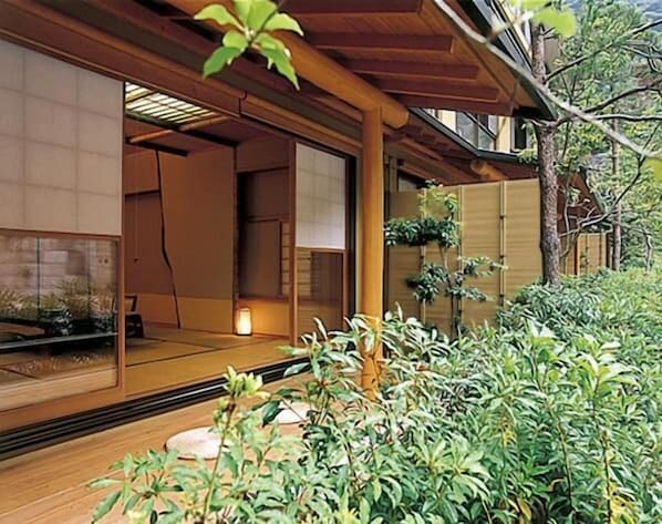 A traditional Japanese-style room with tatami flooring, sliding doors, and a view of a garden with plants and a tree. - Nishiyama Onsen Keiunkan (Hayakawa)