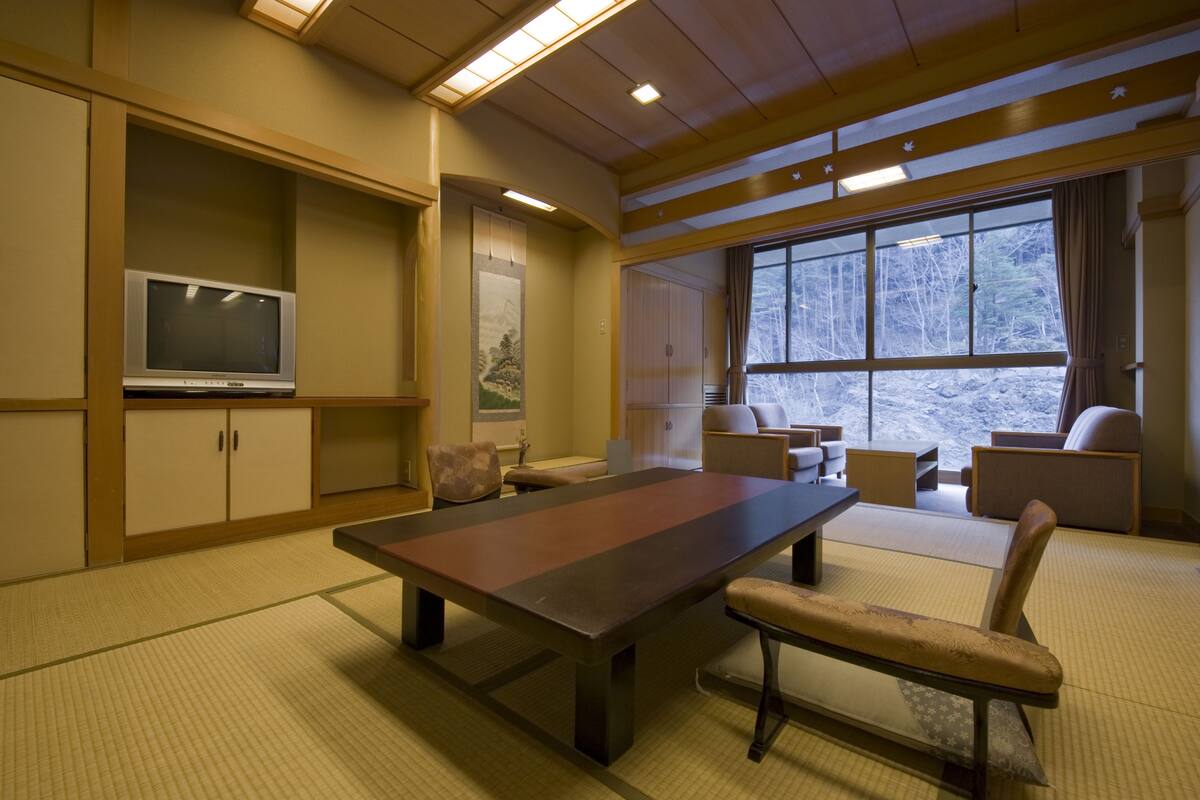 Une pièce de style japonais traditionnel, avec un sol recouvert de tatamis, une table basse et des assises confortables.