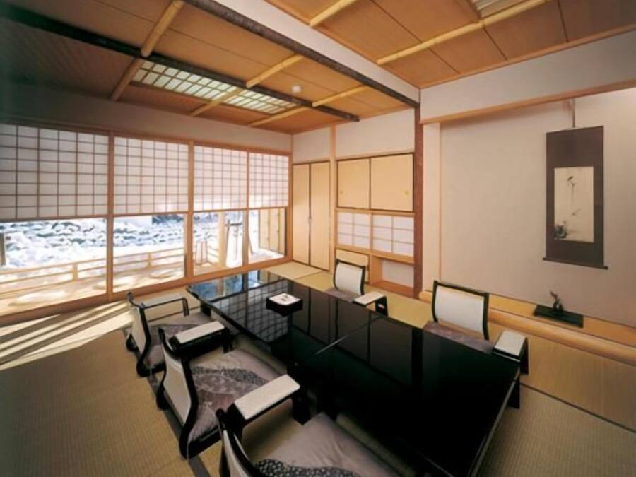 Ein traditioneller japanischer Raum mit Tatami-Böden, einem niedrigen Tisch und verschiebbaren Türen.