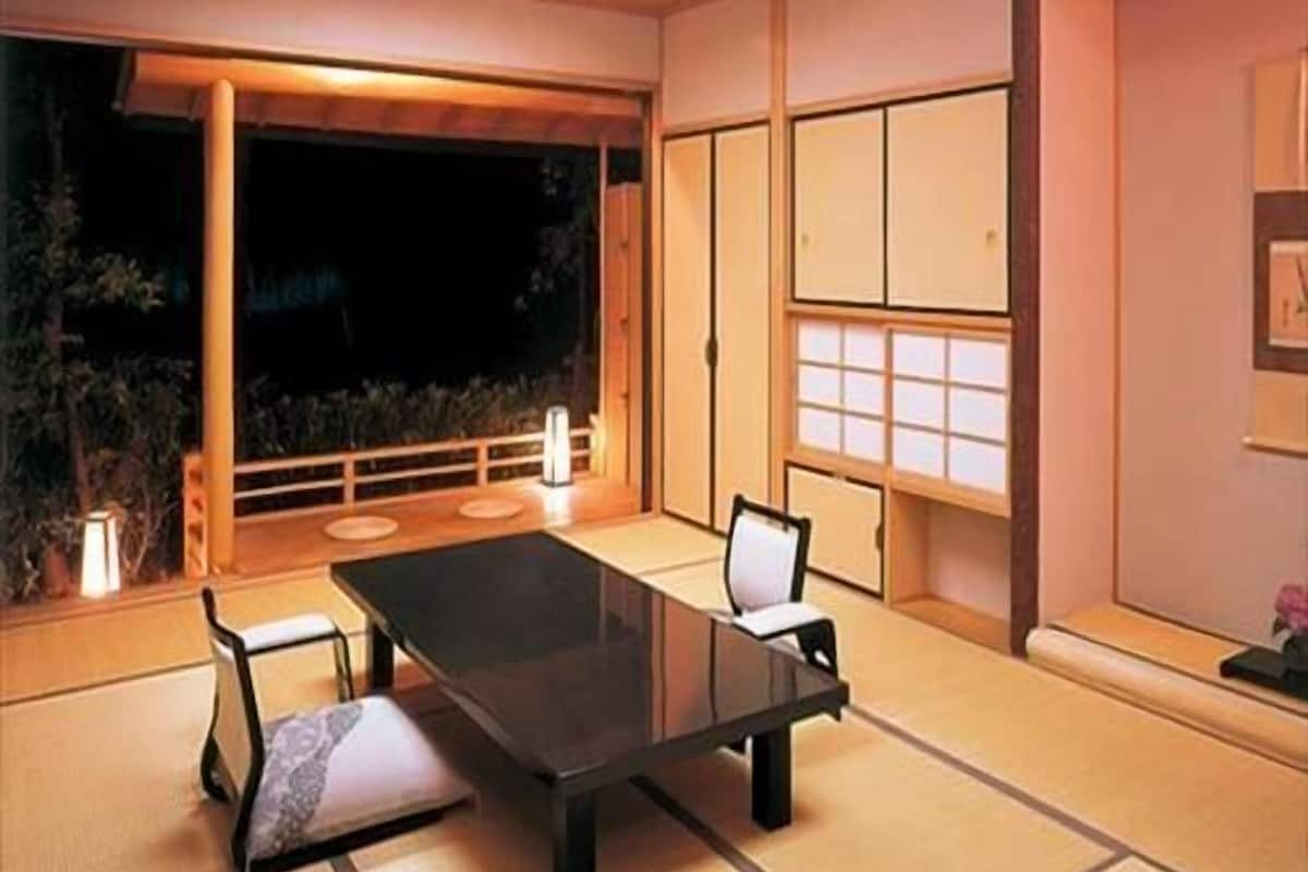 Une pièce de style japonais traditionnel, avec un sol recouvert de tatamis, une table basse et des portes coulissantes.