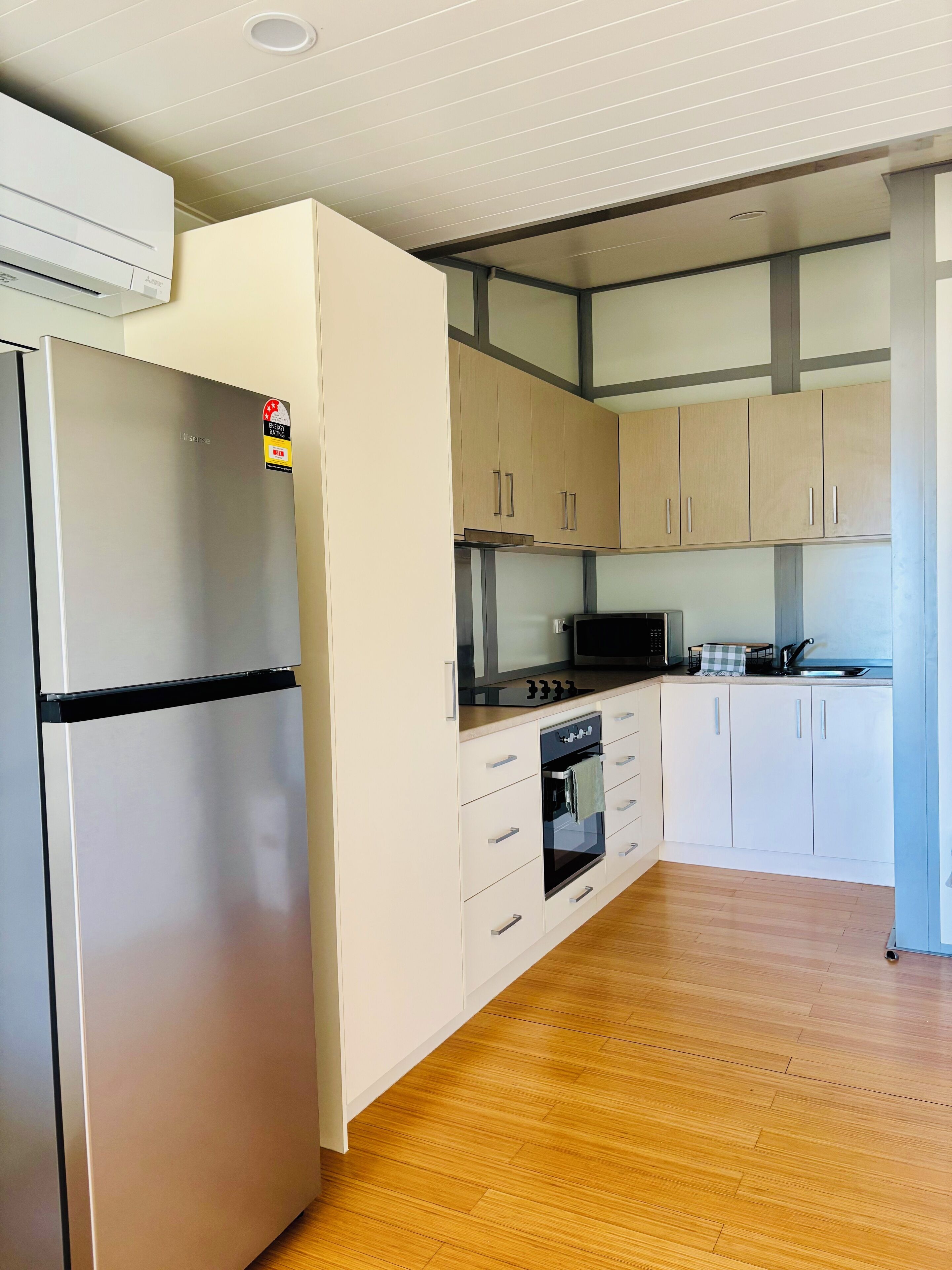 Una cocina moderna con armarios blancos, un refrigerador de acero inoxidable, un microondas y una estufa.
