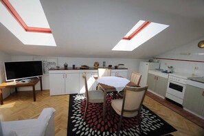 A compact kitchen with a dining area, a TV, and a ceiling skylight. - Apartment Ljustina (Silo - island Krk)