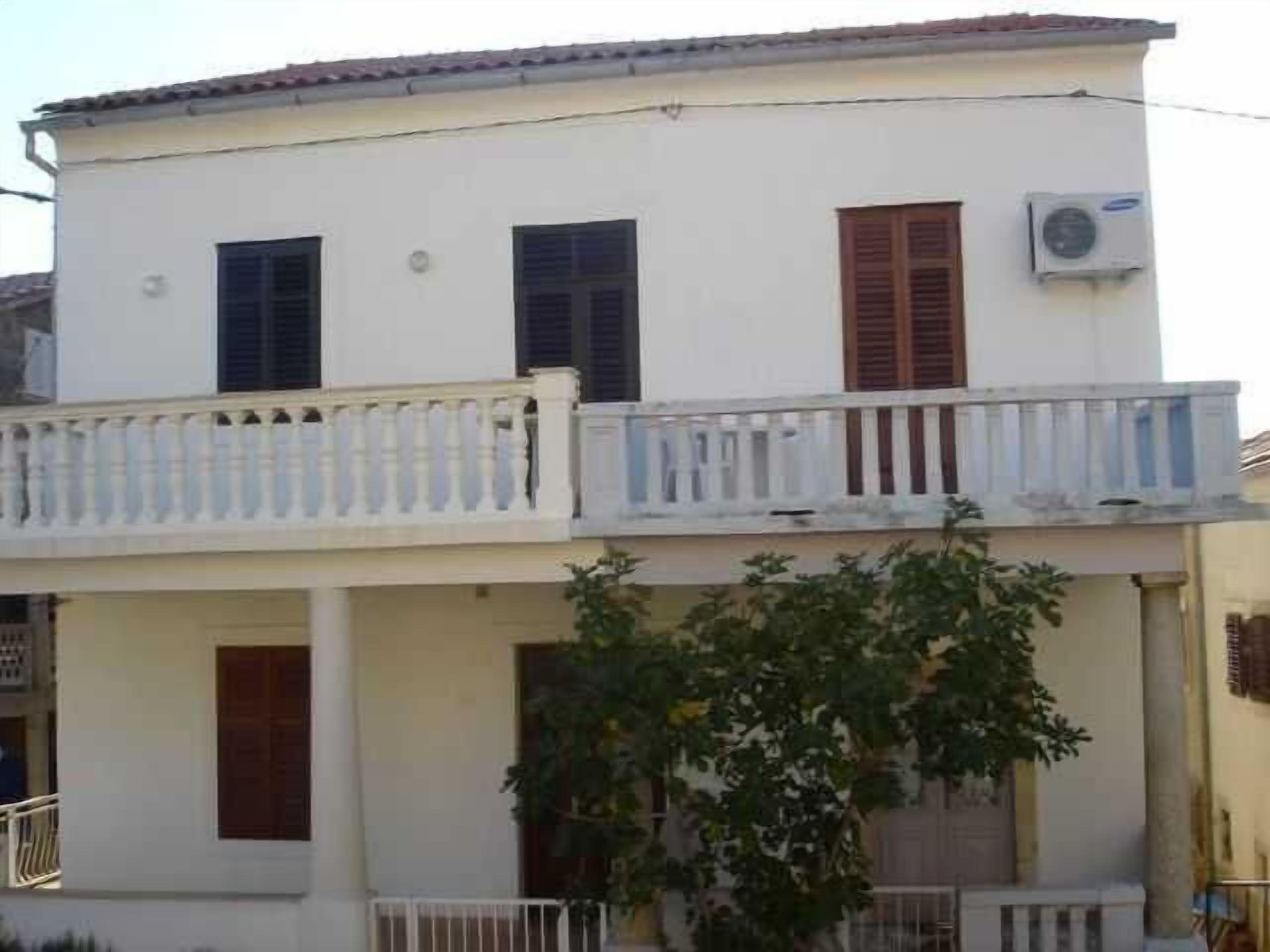 Un bâtiment à deux étages doté d’un balcon, d’une porte et d’un appareil de climatisation.