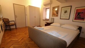A bedroom with a bed, a chair, a wardrobe, and a window with curtains. - Apartment Ljustina (Silo - island Krk)