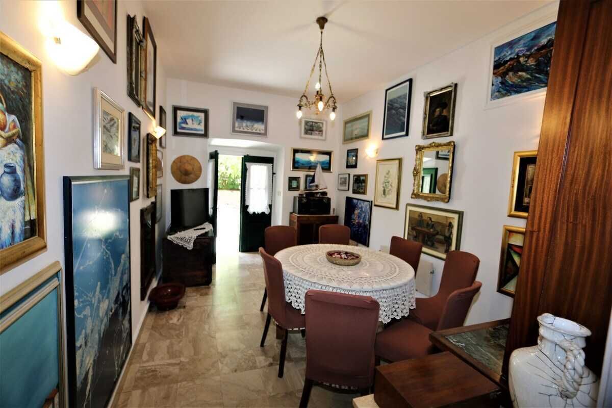 A dining area with a round table, chairs, and artwork on the walls.
