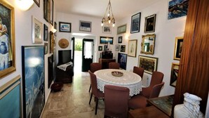 A dining area with a round table, chairs, and artwork on the walls. - Apartment Ljustina (Silo - island Krk)
