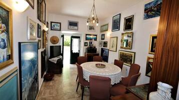 A dining area with a round table, chairs, and artwork on the walls.