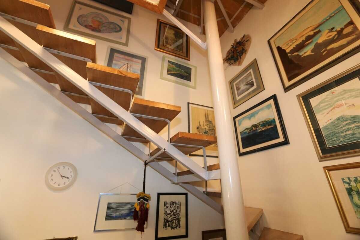 Eine Treppe mit hölzernen Stufen und weißen Geländern, umgeben von gerahmten Bildern an den Wänden.