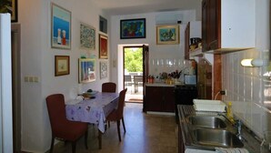 A kitchen with a dining table, chairs, and various kitchen appliances. - Apartment Ljustina (Silo - island Krk)