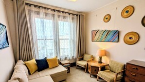 A cozy room with a sofa, two armchairs, a small table with a lamp, and a bookshelf. - Perfect Location - 4BD,1BA - Restored Redwood Home of SF Artists (SF)