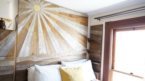 A bedroom with a wooden headboard, a bed with white and yellow pillows, a bedside lamp, and a window with a view of the outside. - Perfect Location - 4BD,1BA - Restored Redwood Home of SF Artists (SF)