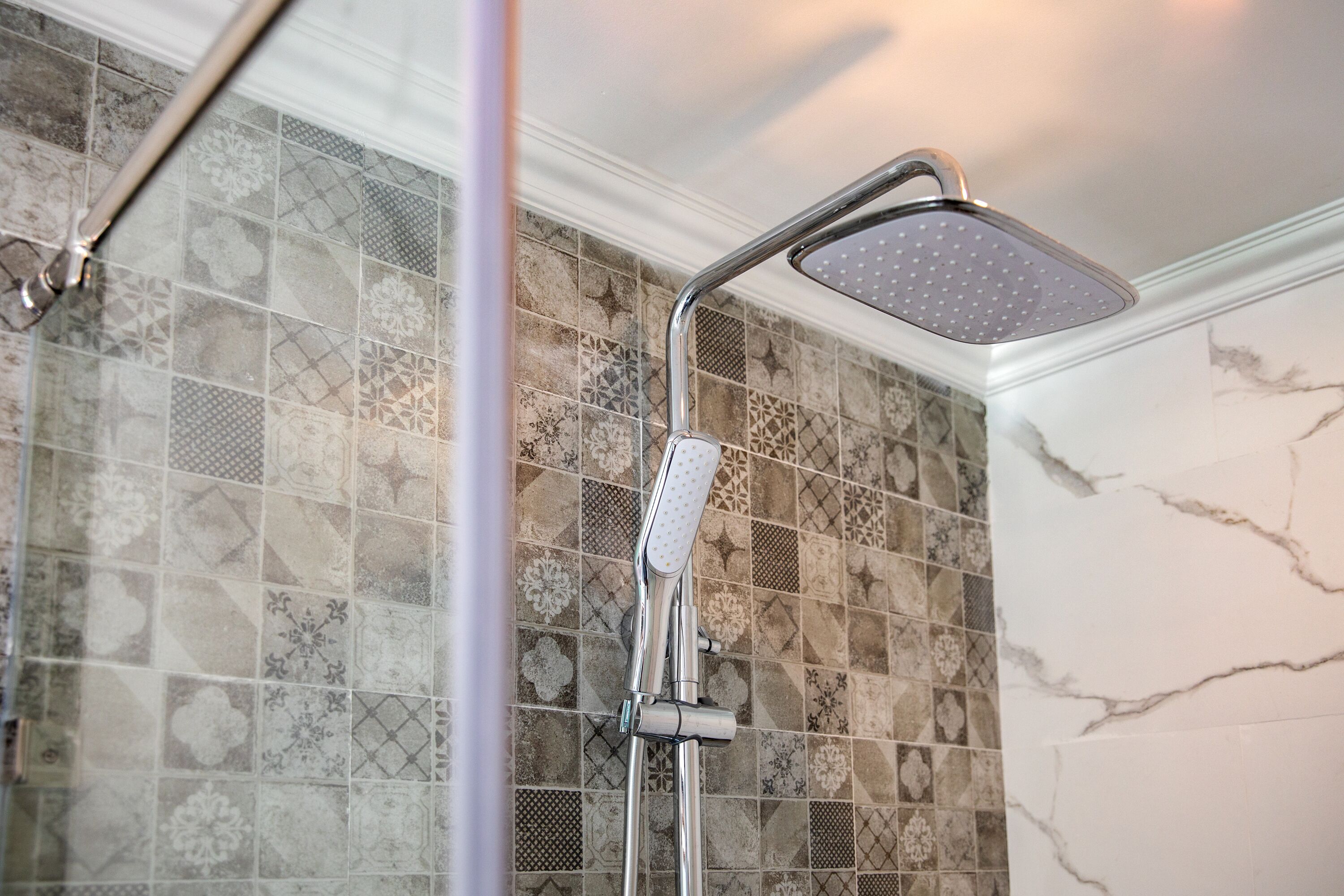A shower with a chrome head and a rain shower head.