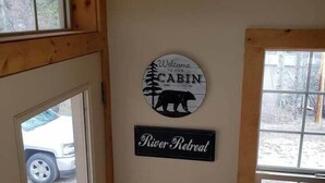L’intérieur d’une cabane, avec une pancarte d’accueil, la silhouette d’un ours et une enseigne indiquant « River Retreat ».