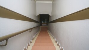 A staircase with a handrail, leading to a landing with a door at the top. - Hotel O London (Sandakan)