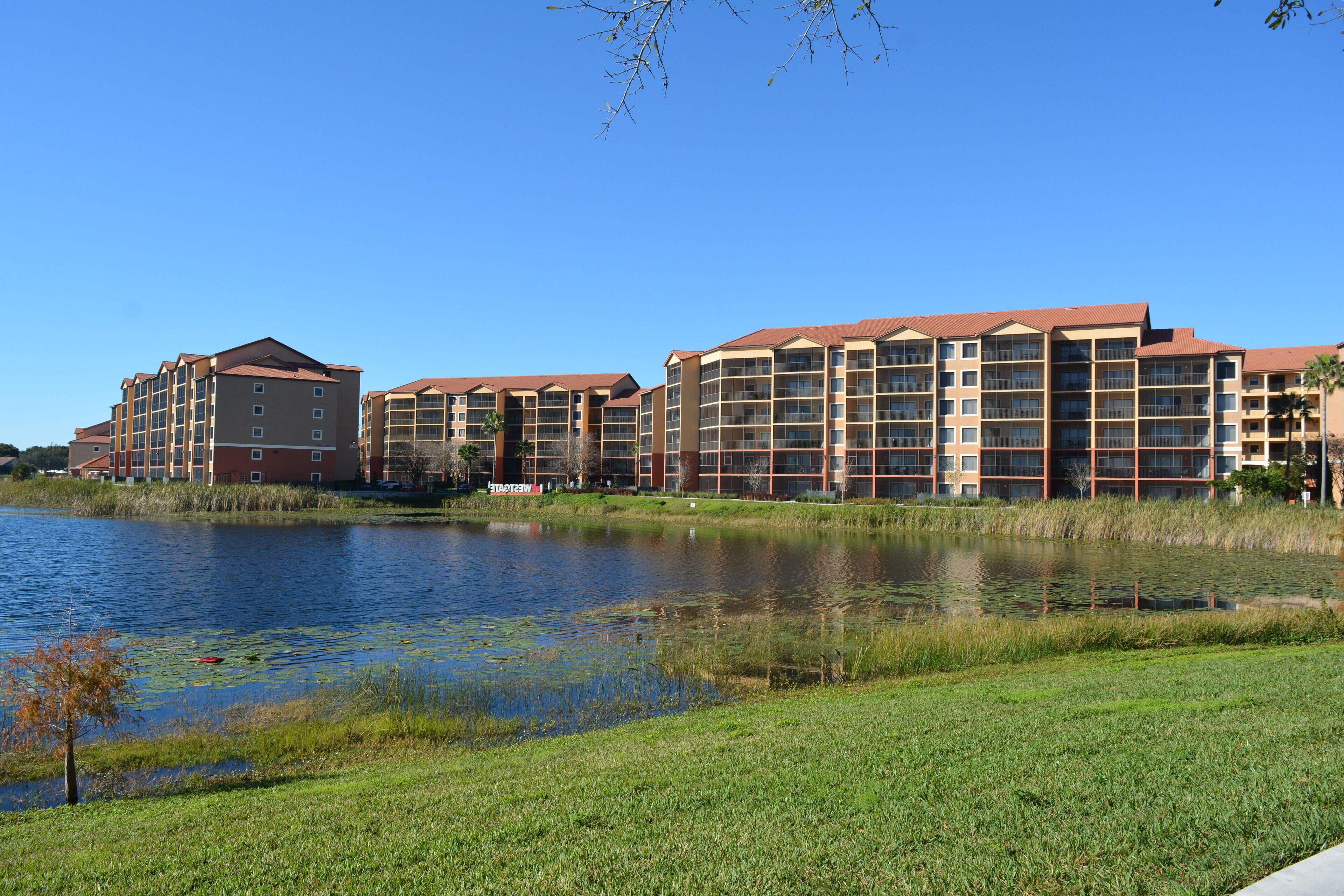 A hotel with multiple buildings, a lake, and a grassy area.