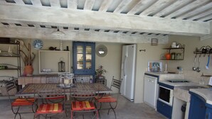 Une cuisine avec un coin repas, un sol en pierre et des meubles de couleur bleue.