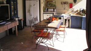 Une cuisine équipée d’une table à manger, de chaises, d’un réfrigérateur et d’un téléviseur.