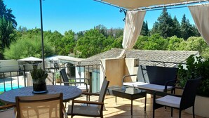 Un espace patio aménagé avec du mobilier d’extérieur, une piscine et une vue sur la verdure.