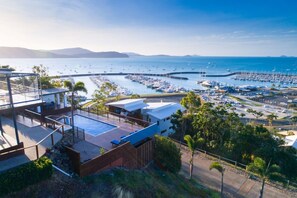 A coastal property with a rooftop pool, a marina with boats, and a view of the sea. - Nautilus On The Hill - Luxury Holiday Home in Central Airlie (Airlie Beach)