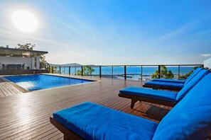 A poolside area with lounge chairs and a view of the sea.