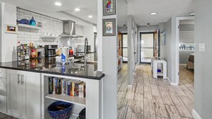 A modern kitchen with white cabinetry, a marble countertop, and a built-in bookshelf.