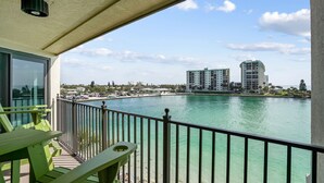 A balcony with a view of a waterfront, including buildings and a marina.