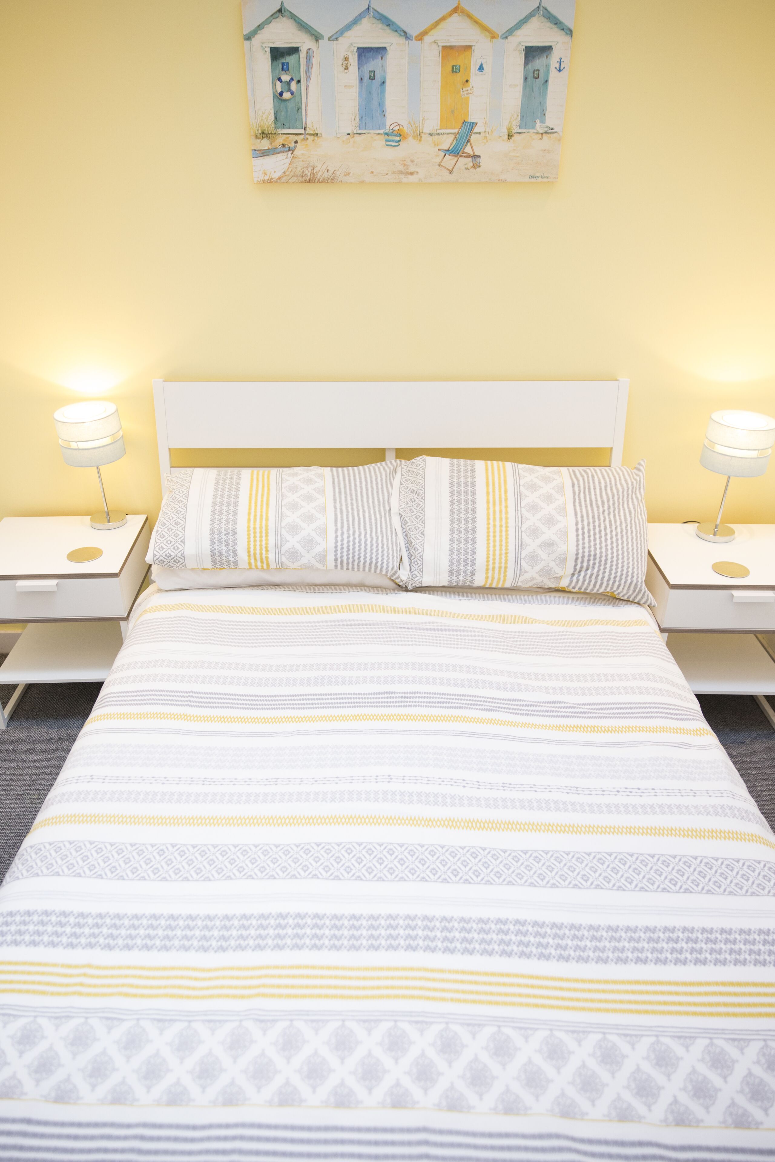 A neatly made bed with patterned bedding and two bedside tables with lamps.