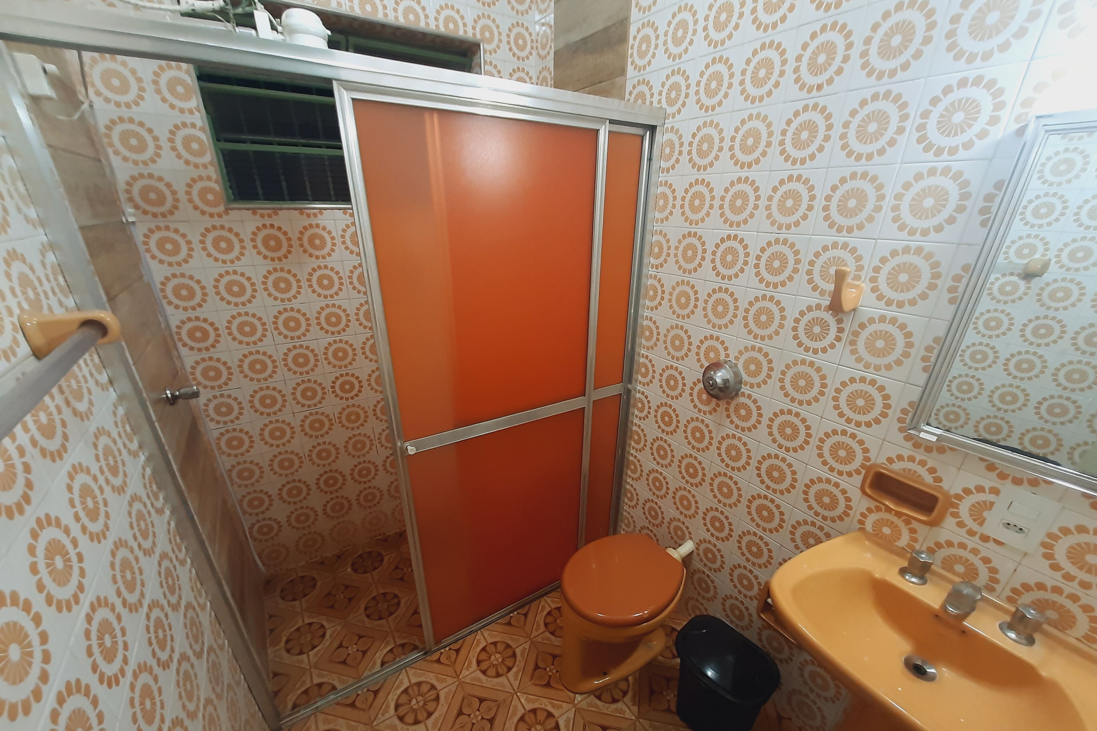 A bathroom with patterned tiles, a toilet, a sink, and a shower enclosure.