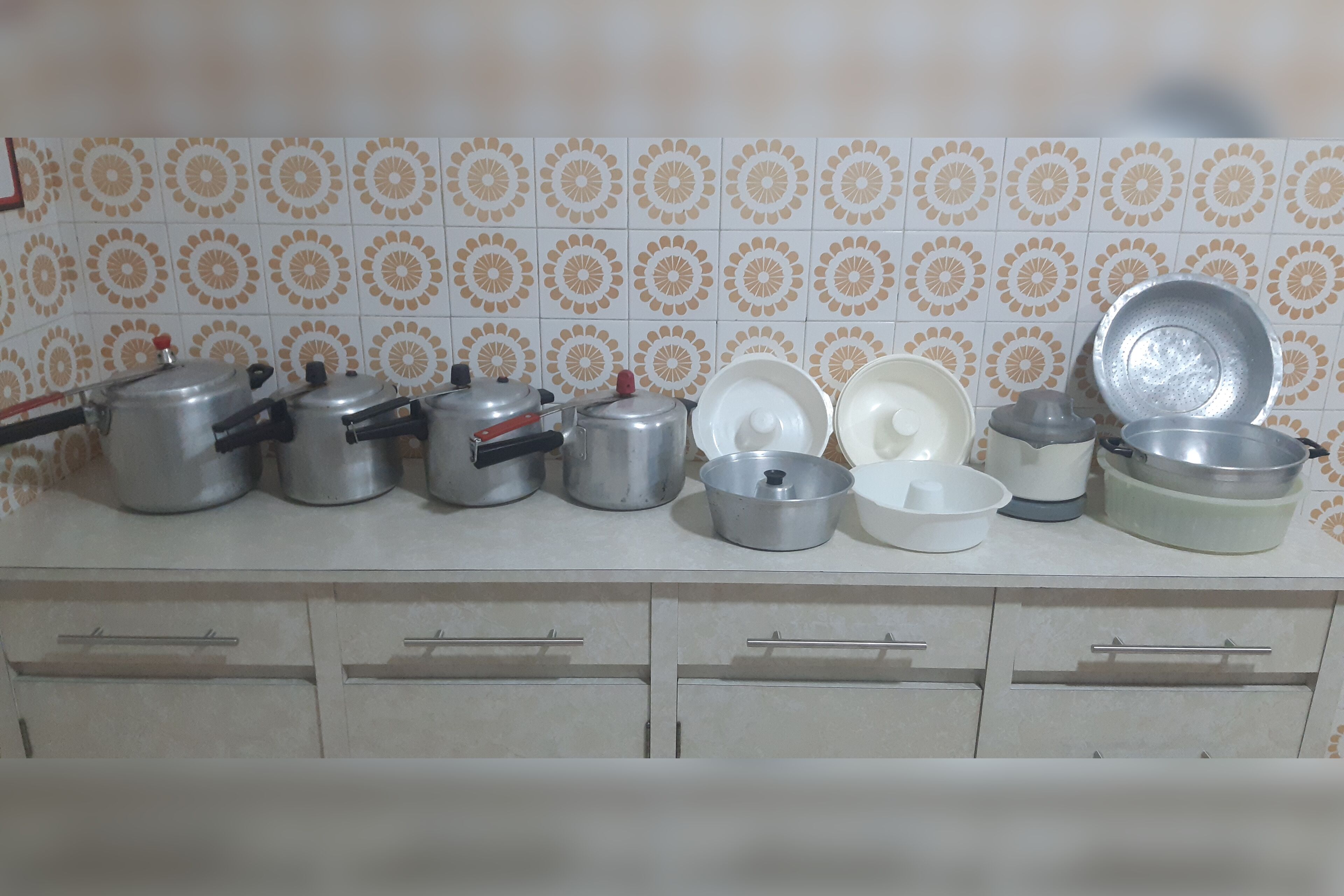 A kitchen counter with various pots, pans, and cooking utensils.