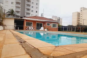 Una piscina al aire libre, sillones reclinables de piscina